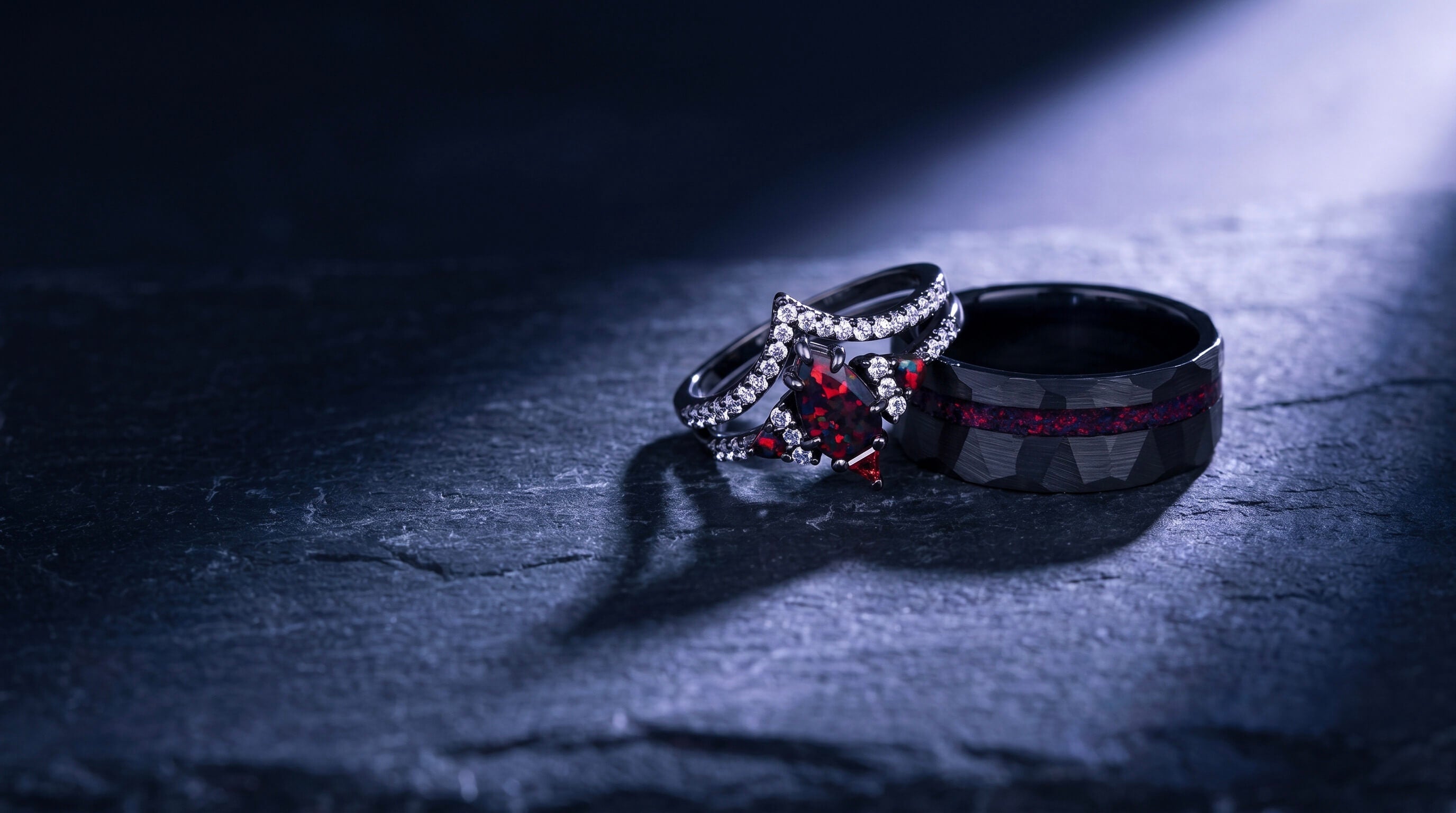 Black wedding ring couples set photographed in atmospheric low light on dark slate