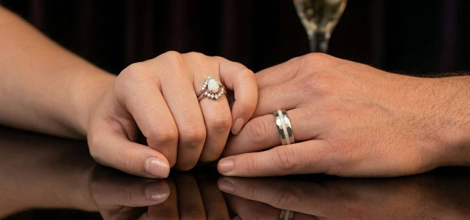 White opal engagement ring and wedding band set worn by couple