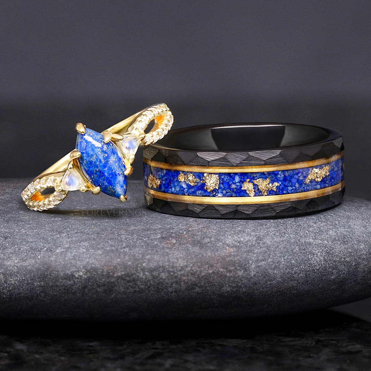 Gold lapis lazuli engagement ring beside a hammered black tungsten band with lapis and gold leaf inlay