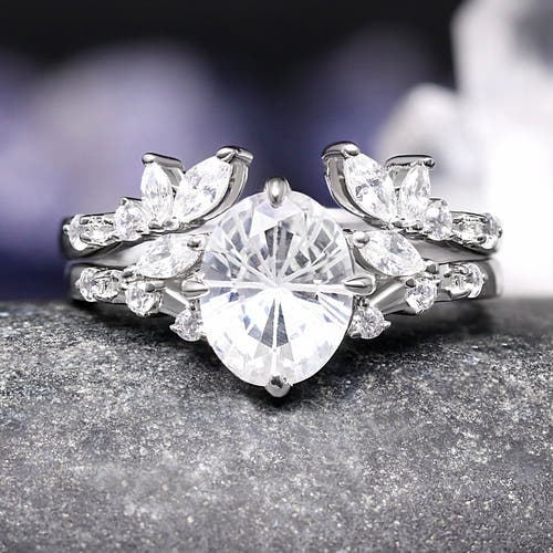 Silver ring with a large central diamond and smaller diamonds on a dark surface