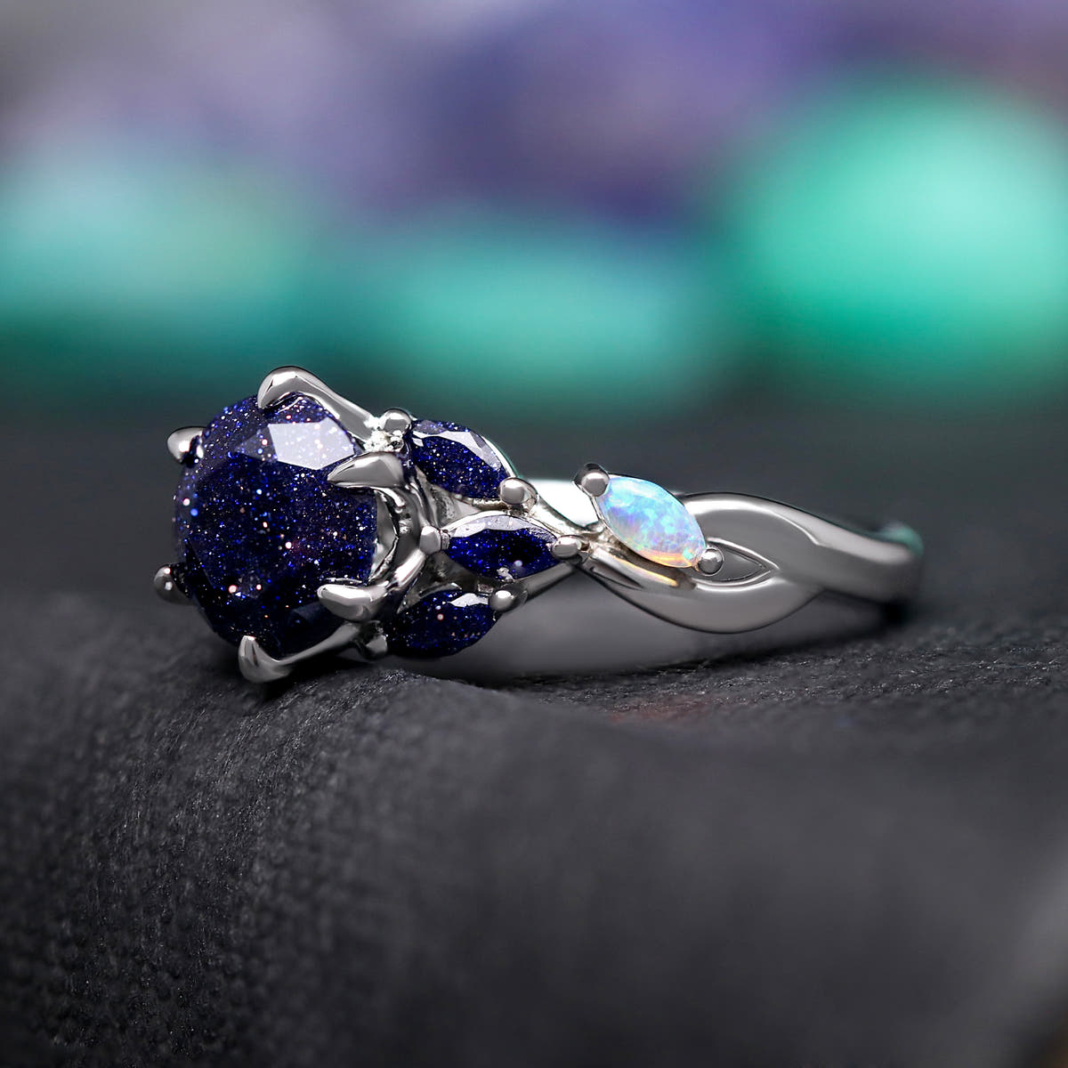 Women's sterling silver ring with a round blue sandstone and white opal accents, angled side view