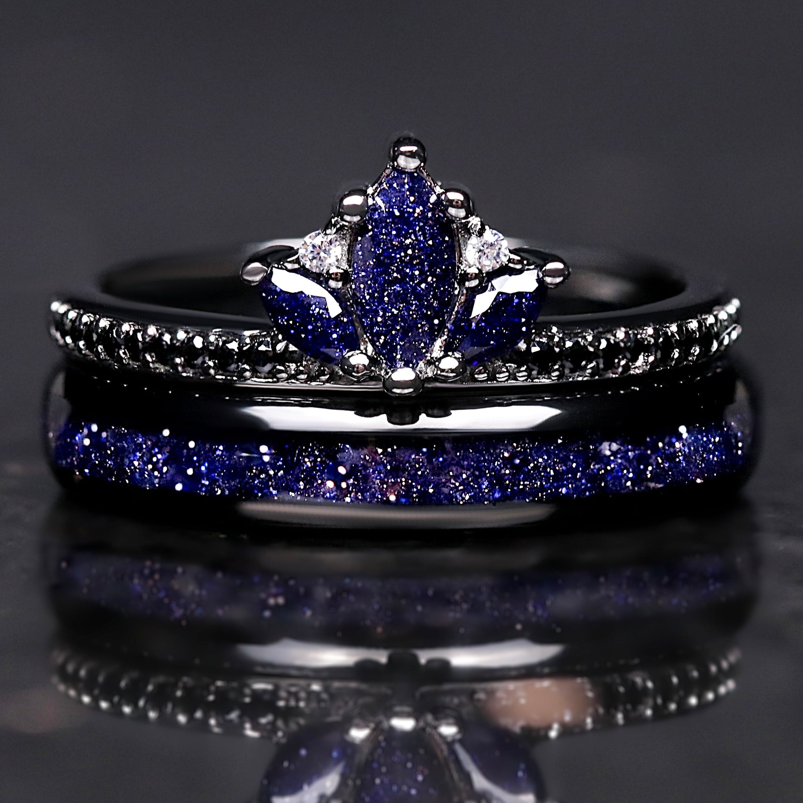 Two rings with blue gemstones on a reflective surface