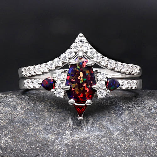 Sterling silver bridal set with a black fire opal center and garnet accents, shown straight on