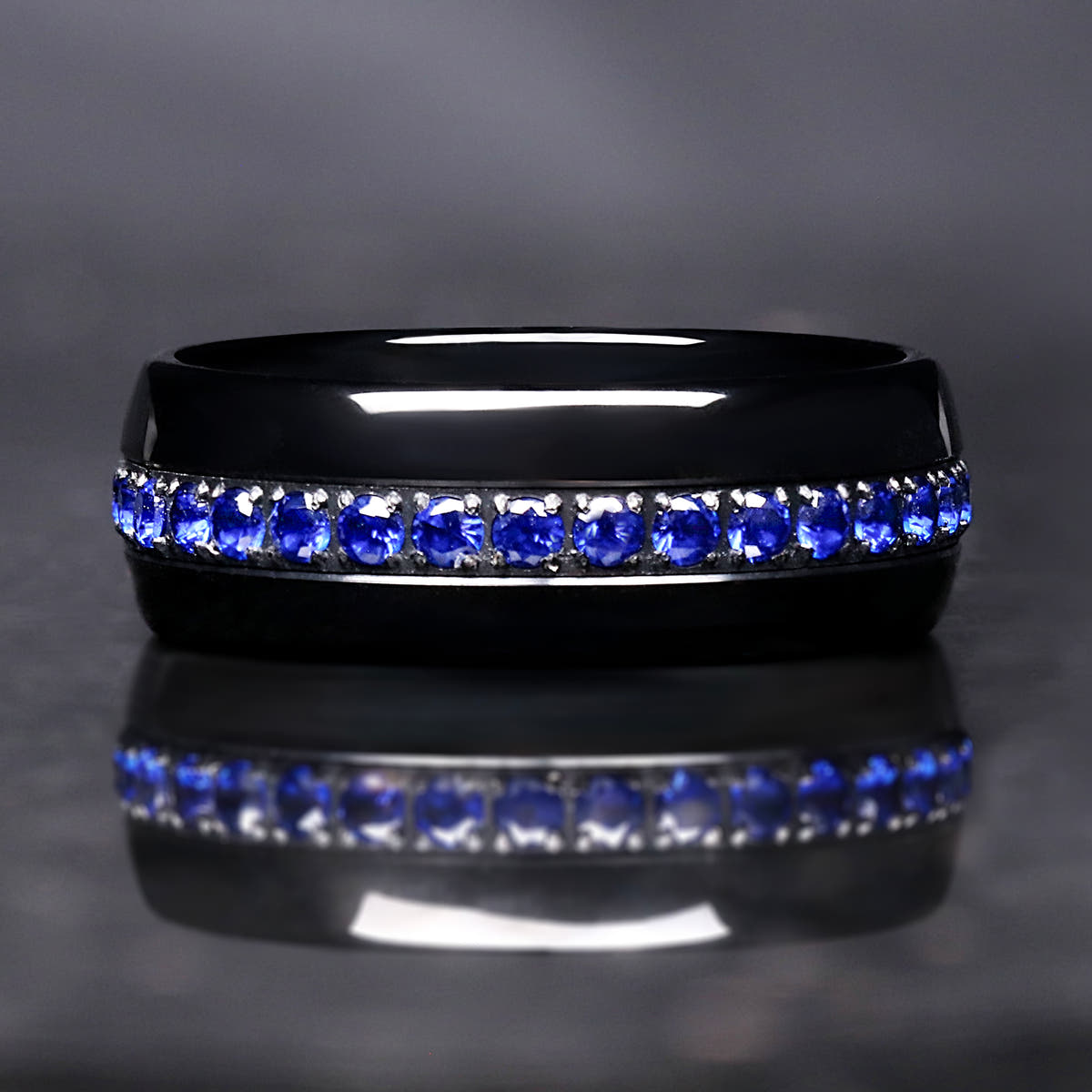 Men's 8mm black tungsten band with a channel of blue sapphire stones, straight-on view