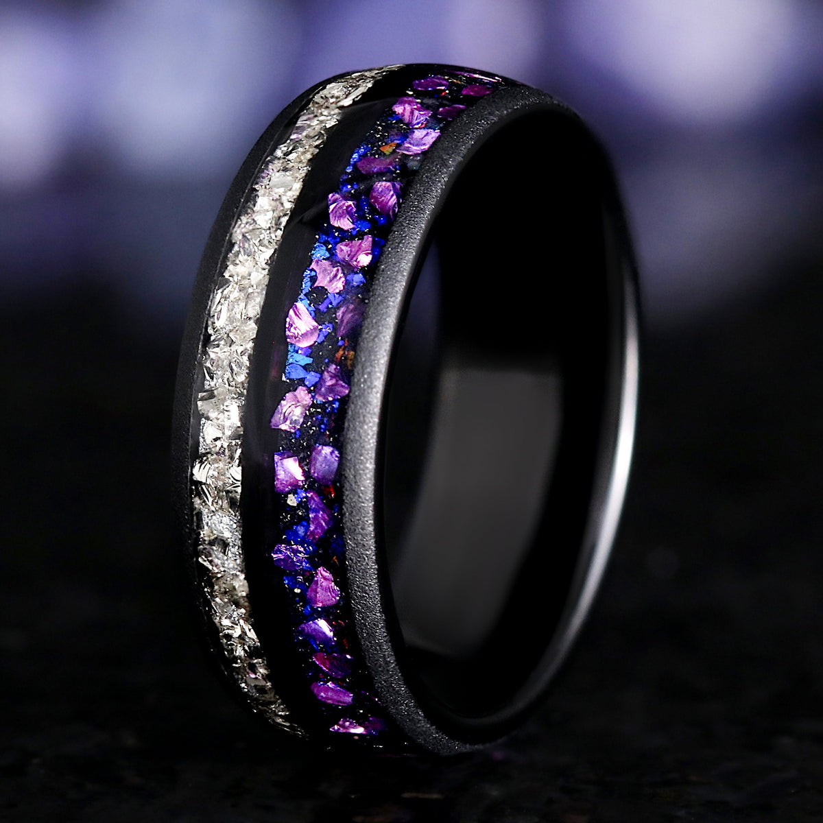 Black ring with purple and white gemstones on a dark background