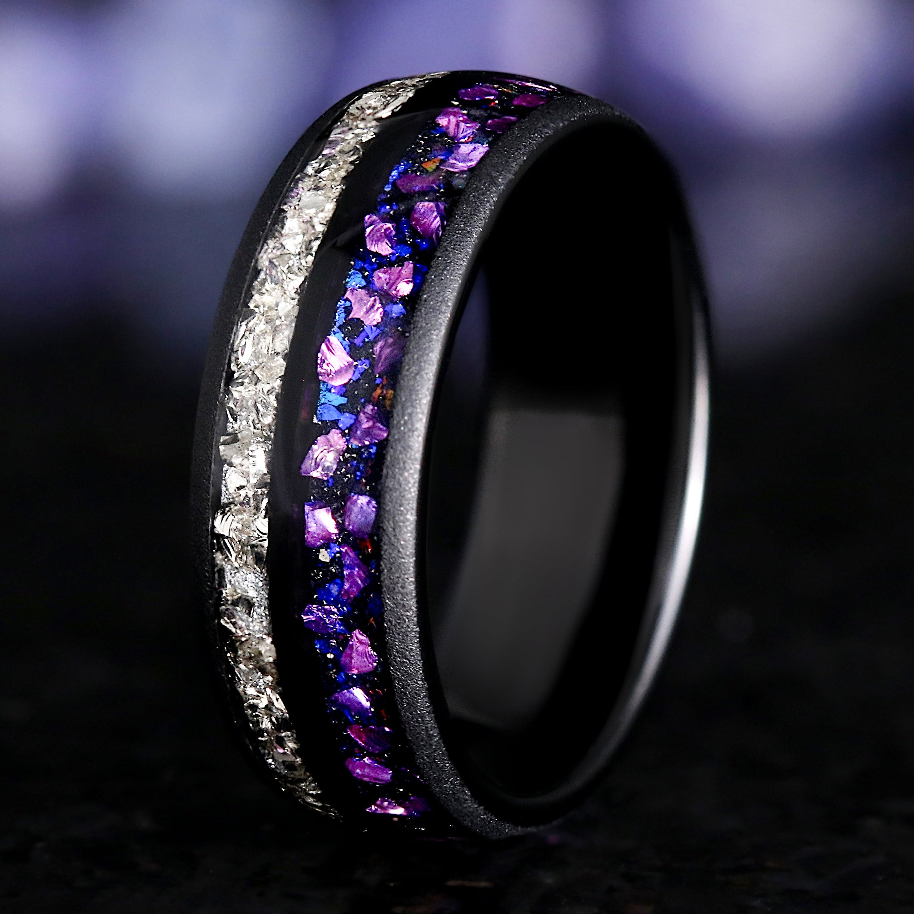 Black ring with purple and white gemstones on a dark background