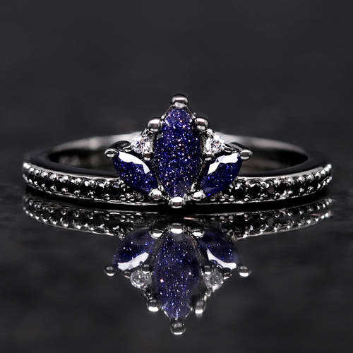 Ring with blue gemstone on a reflective black surface