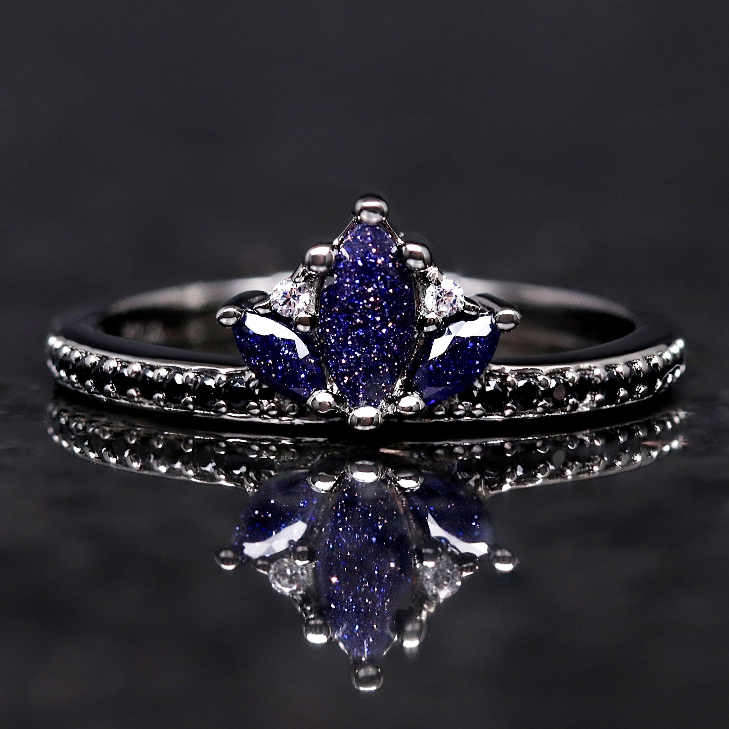 Ring with blue gemstone on a reflective black surface