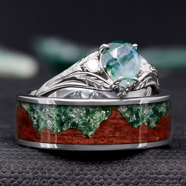 Pear-cut moss agate ring resting on a men's band with wood and moss agate mountain inlay