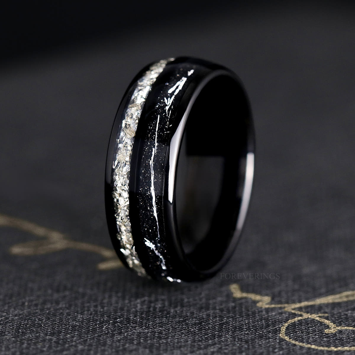 Men's 8mm black tungsten band with crushed diamond and silver flake inlay, standing on edge