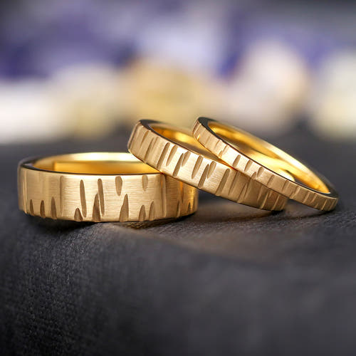Geared gold tungsten wedding bands in 6mm, 4mm and 2mm widths, lined up leaning on each other