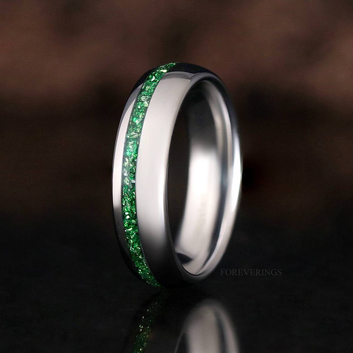 Slimmer silver tungsten band with emerald inlay standing at an angle