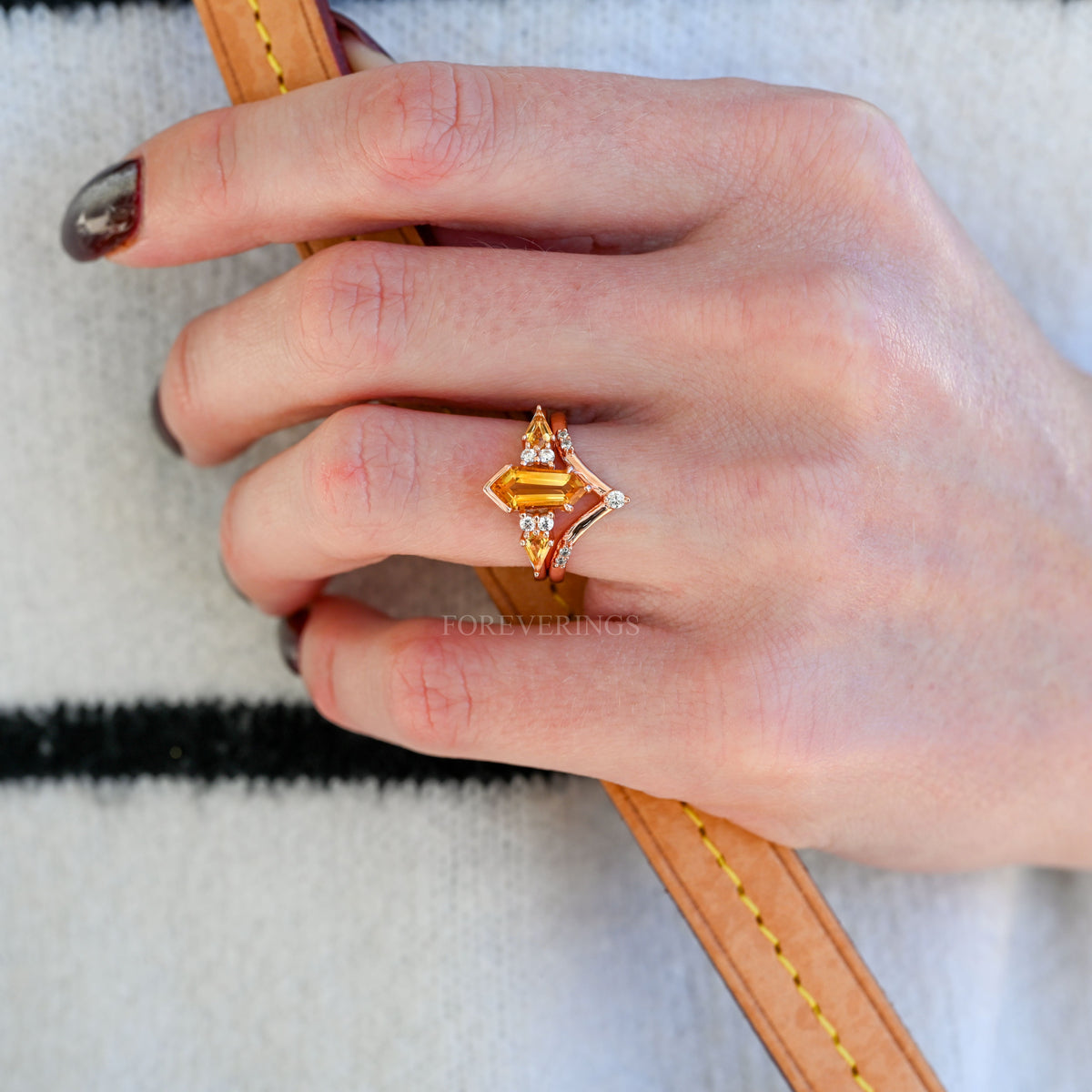 Rose gold kite-cut citrine engagement ring worn on a hand