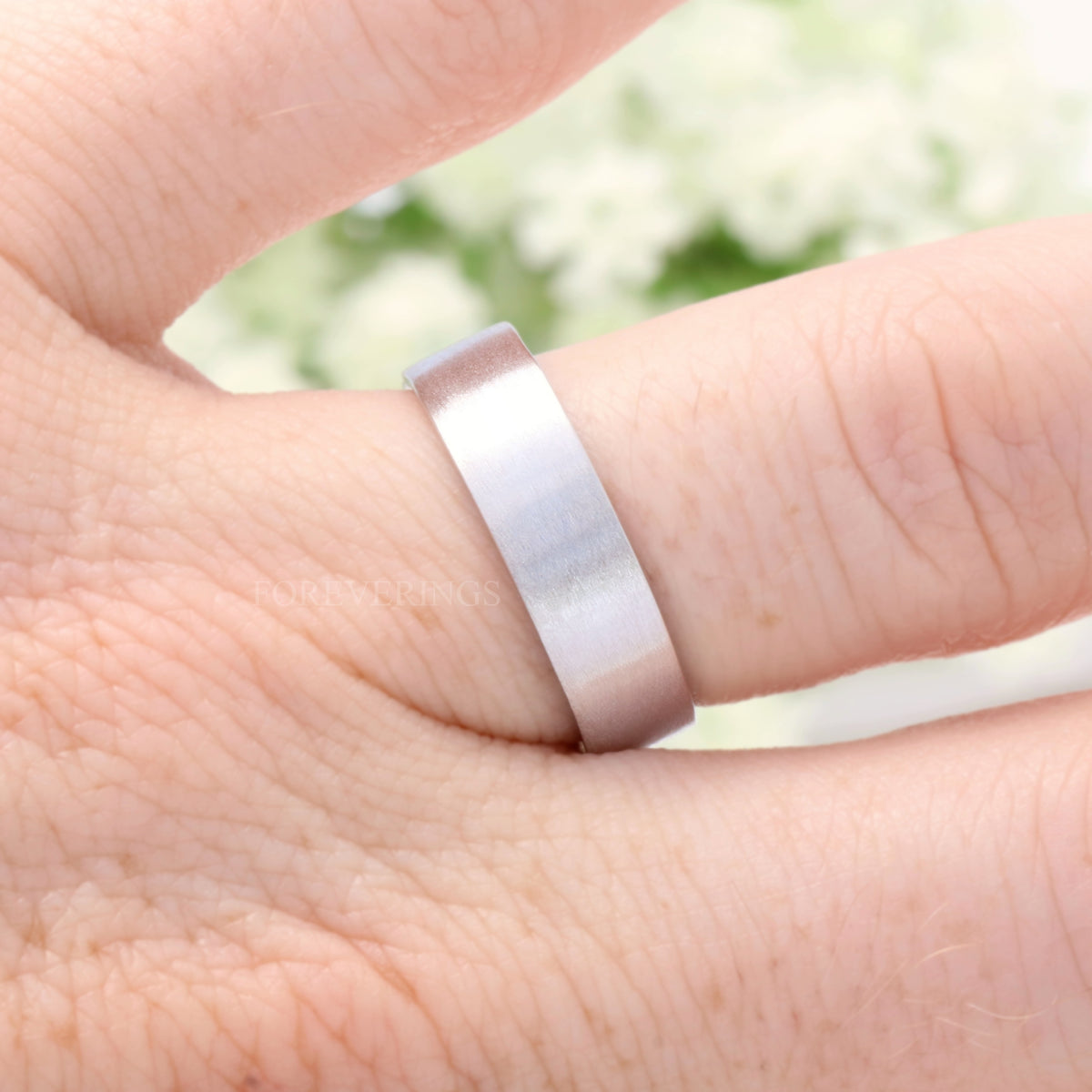 Men's 6mm brushed sterling silver band on a finger, close-up