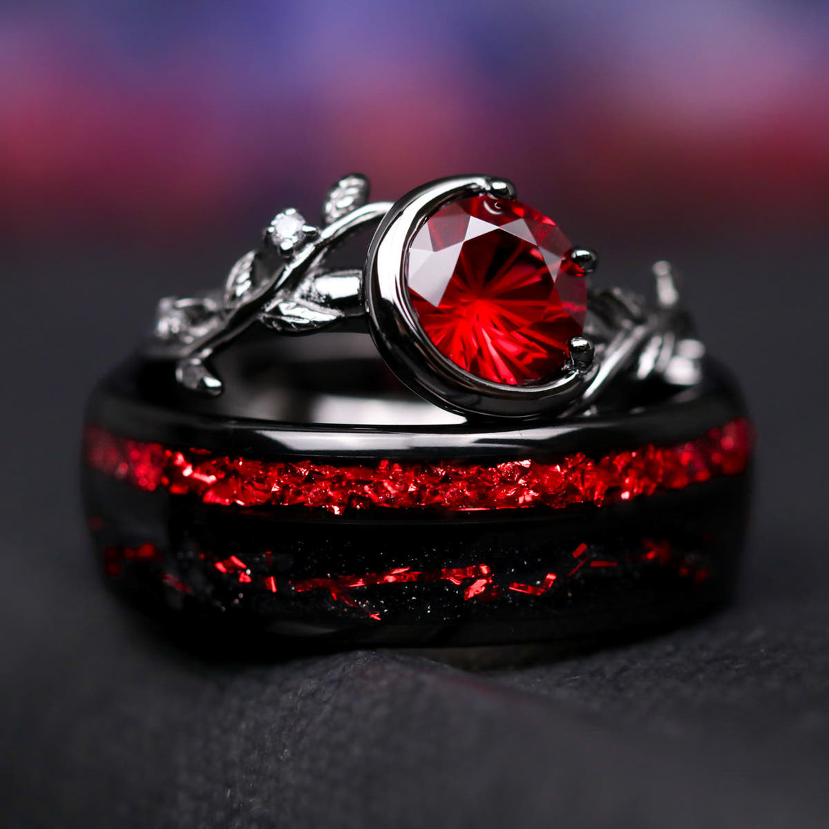 Rhodolite crescent moon ring resting on a wider black band with red inlay