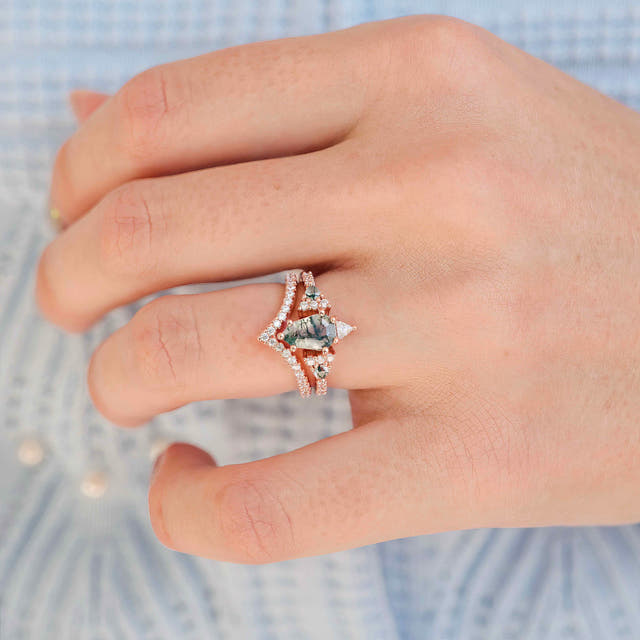 Pear moss agate engagement ring and curved band in rose gold, worn on a woman's hand