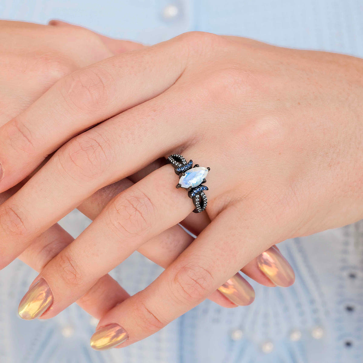 Marquise moonstone ring in a black setting worn on a woman's hand