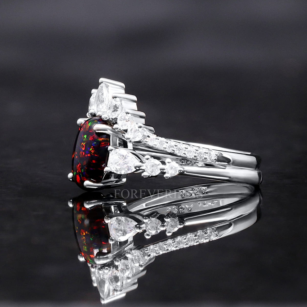 Black fire opal bridal set from the side, showing the curved band of pear-shaped clear stones