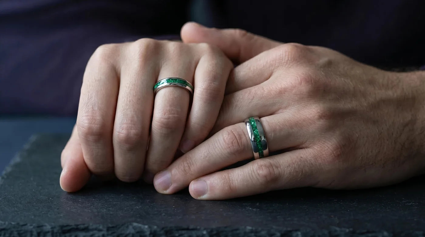Matching his and hers wedding bands with emerald inlay worn on their hands