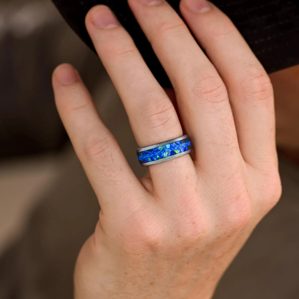Men's 8mm silver tungsten band with blue fire opal and dichrolam inlay worn on a hand
