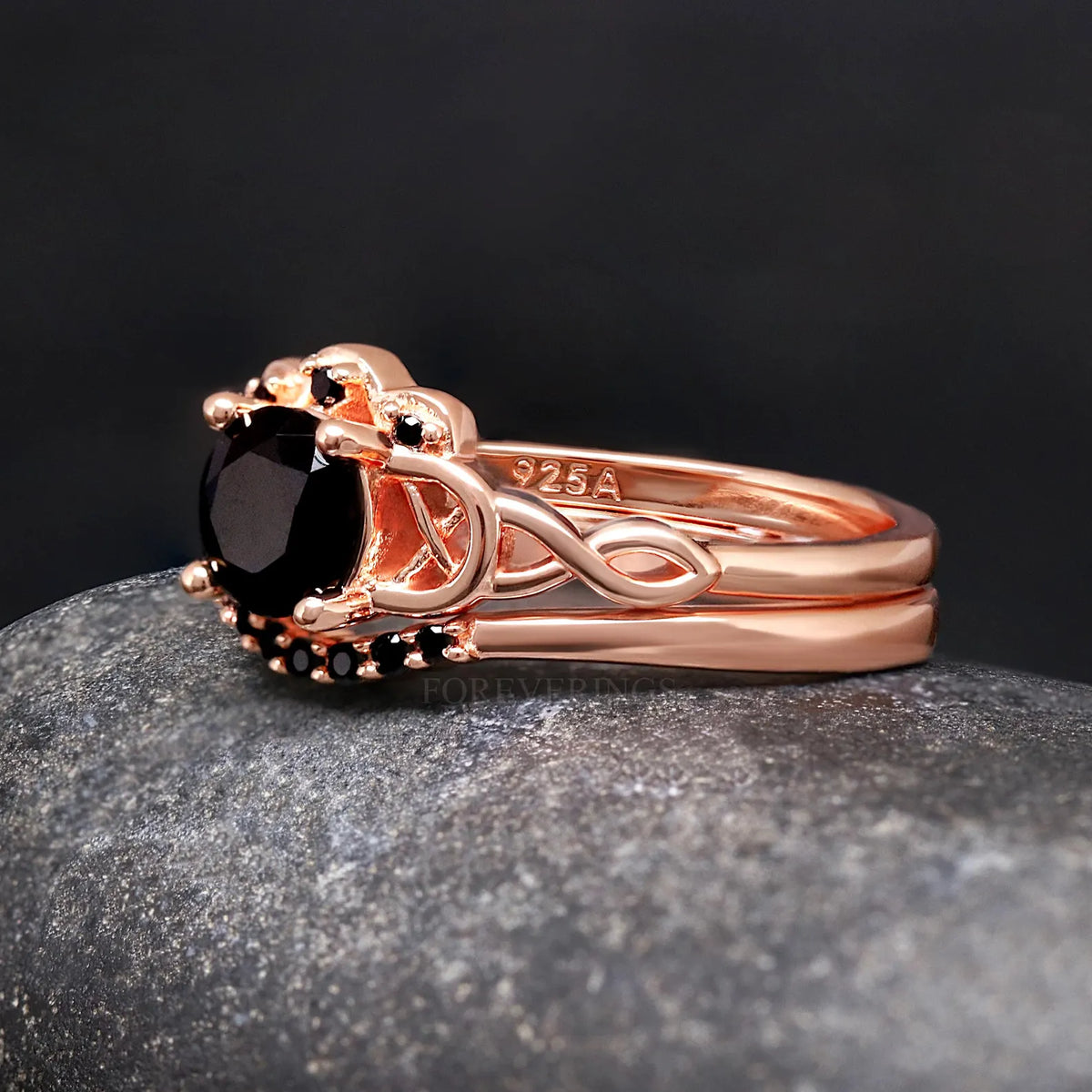 Side view of a rose gold engagement ring nested with a curved band of black accent stones