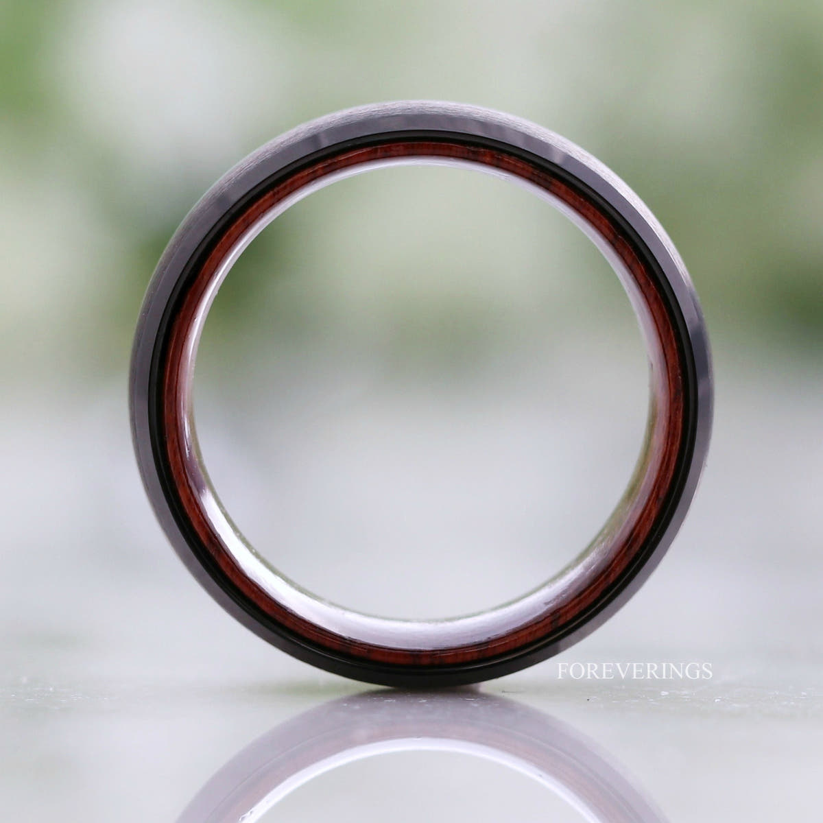 Black tungsten rosewood band standing on edge, viewed straight through the ring
