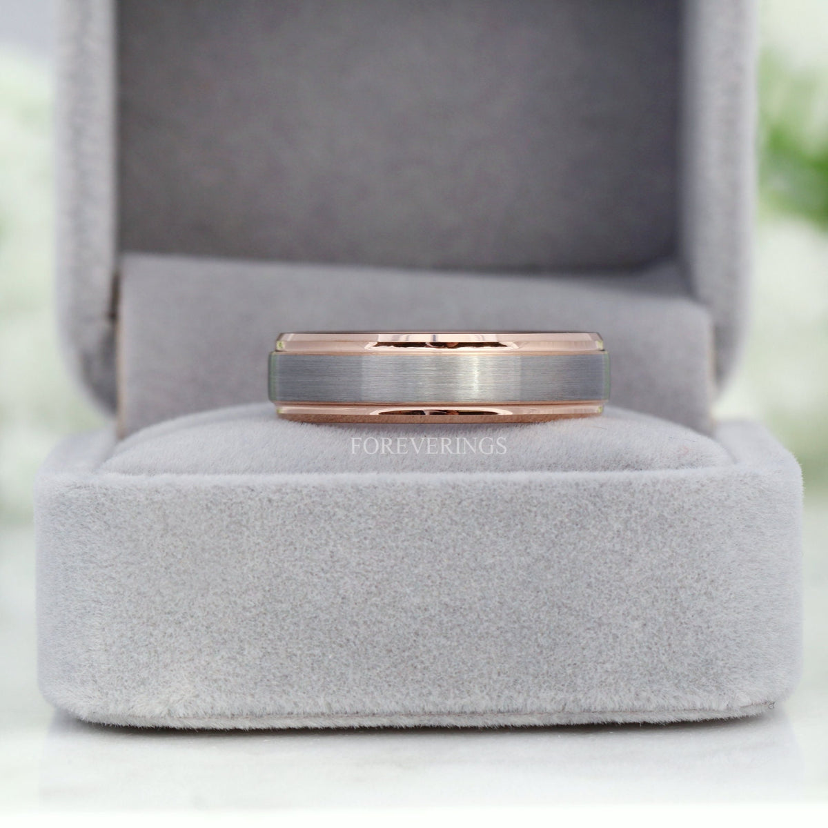 Men's two-tone silver and rose gold tungsten band in a gray velvet ring box