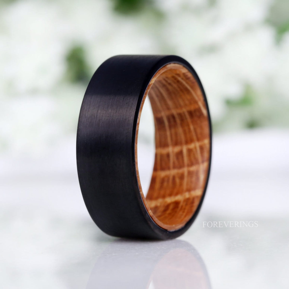 Men's 8mm black brushed tungsten band lined with whiskey barrel wood, standing angled