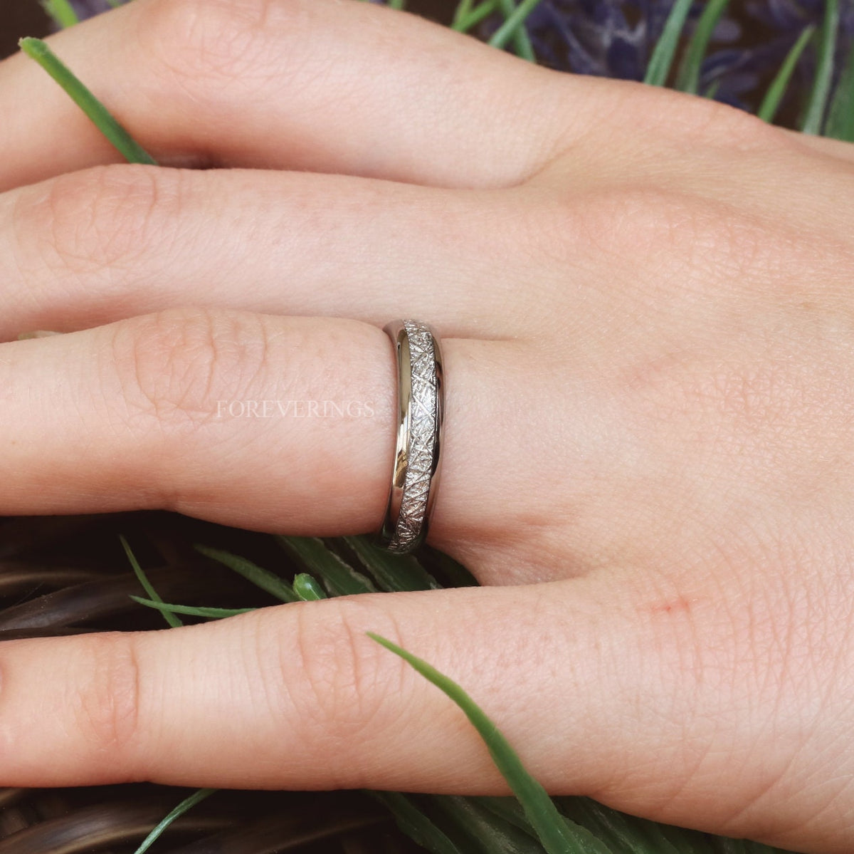 Silver tungsten meteorite-look band worn on a finger, close-up