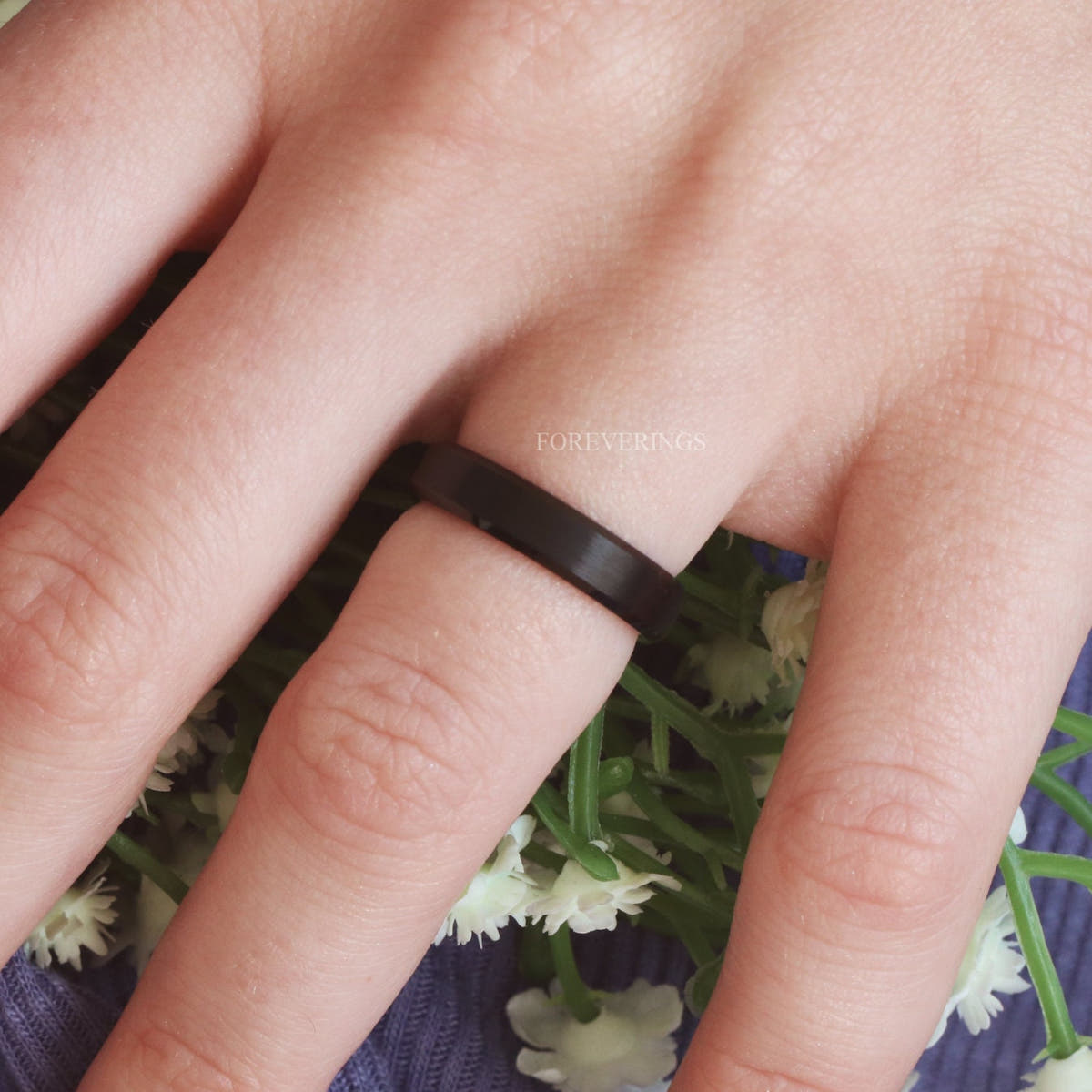 Close-up of the 4mm black tungsten band on a woman's finger, seen from above