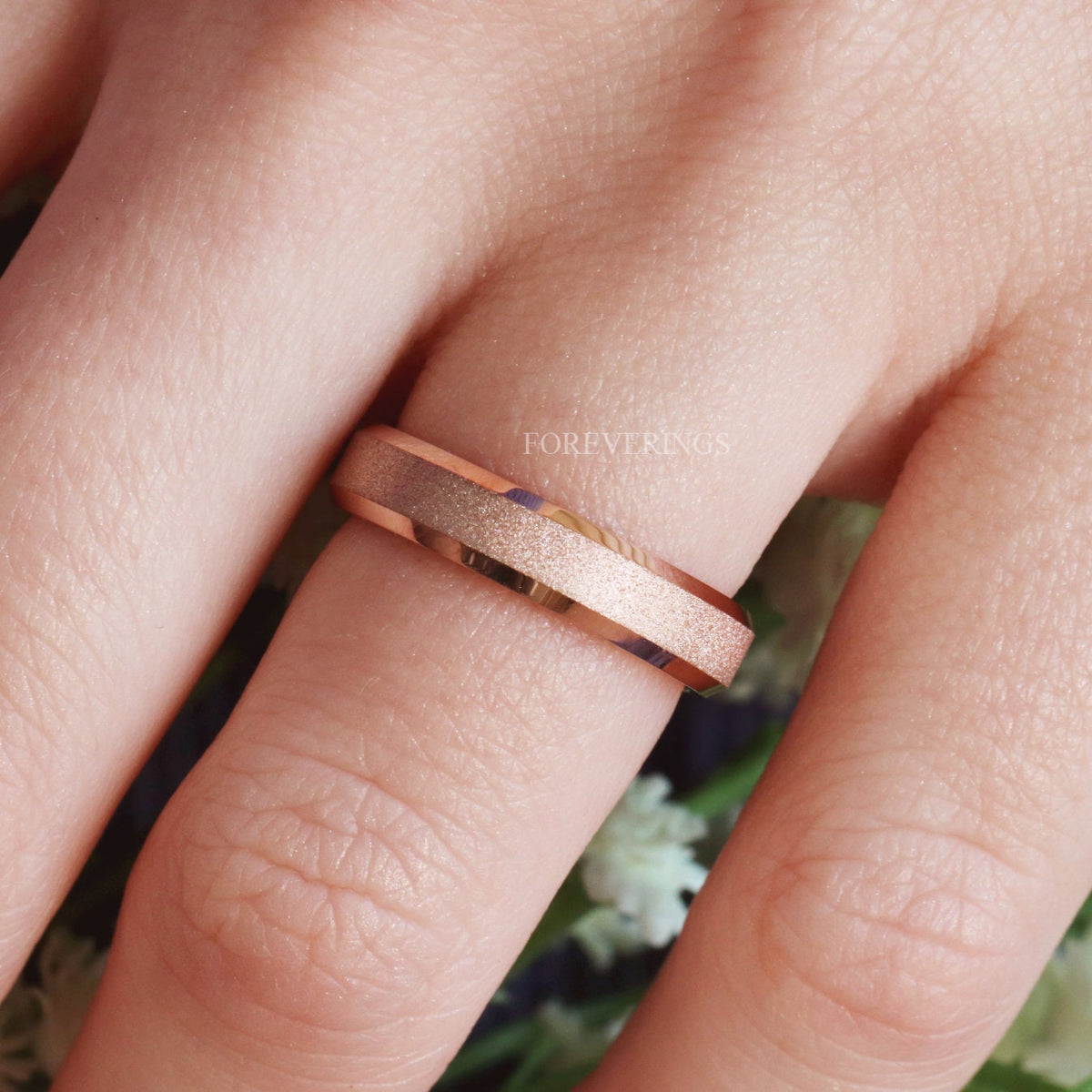 Men's 6mm rose gold tungsten band with beveled edges worn on a finger