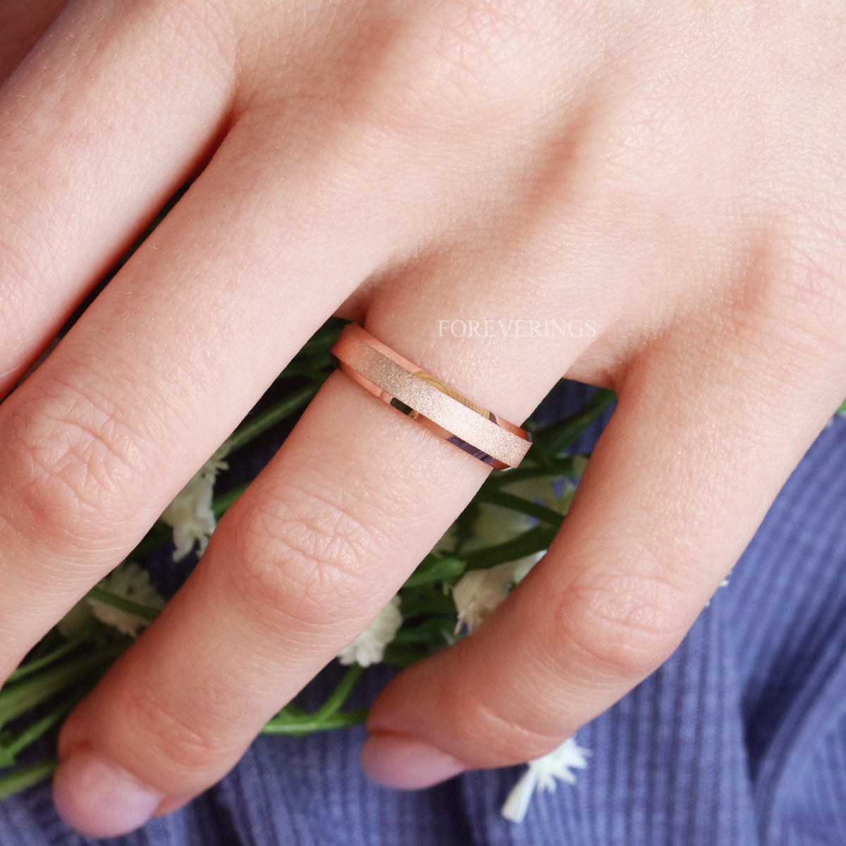Sandblasted rose gold band worn on a woman's finger
