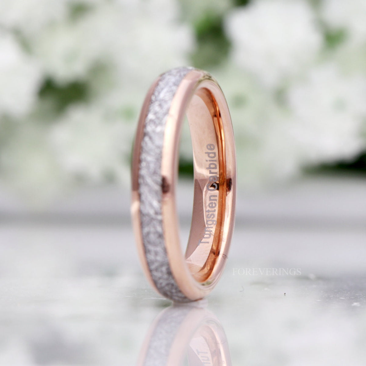 Rose gold tungsten band with meteorite-look inlay standing angled, wider view