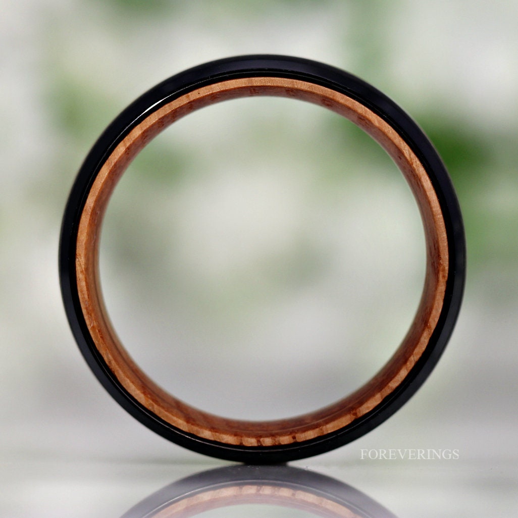 Black tungsten band viewed head-on, showing the full whiskey barrel wood lining
