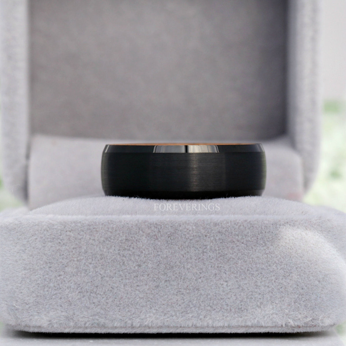 Black tungsten whiskey barrel band in a gray velvet ring box