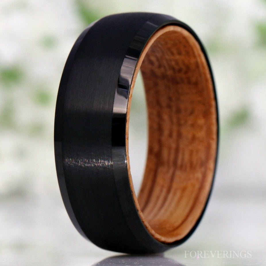 Men's brushed black tungsten band with whiskey barrel wood lining, standing close-up