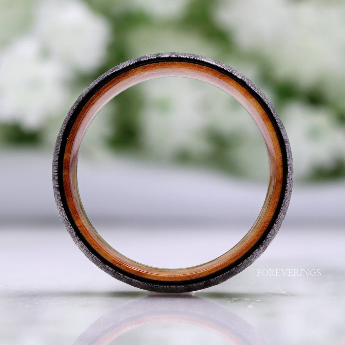 Black tungsten band seen straight on, showing the olive wood interior all around