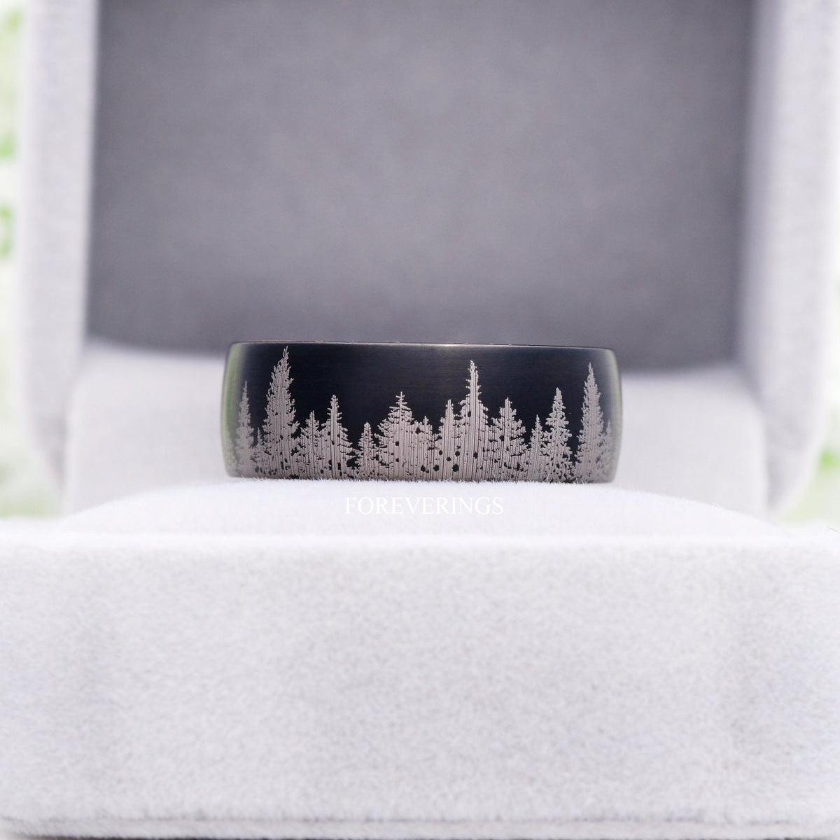 Black tungsten forest band with whiskey barrel wood in a light gray ring box