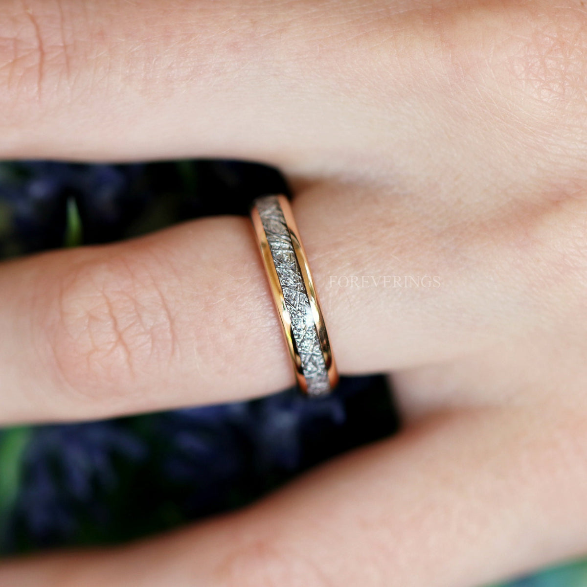 Rose gold meteorite-look tungsten band worn on a finger, angled from above