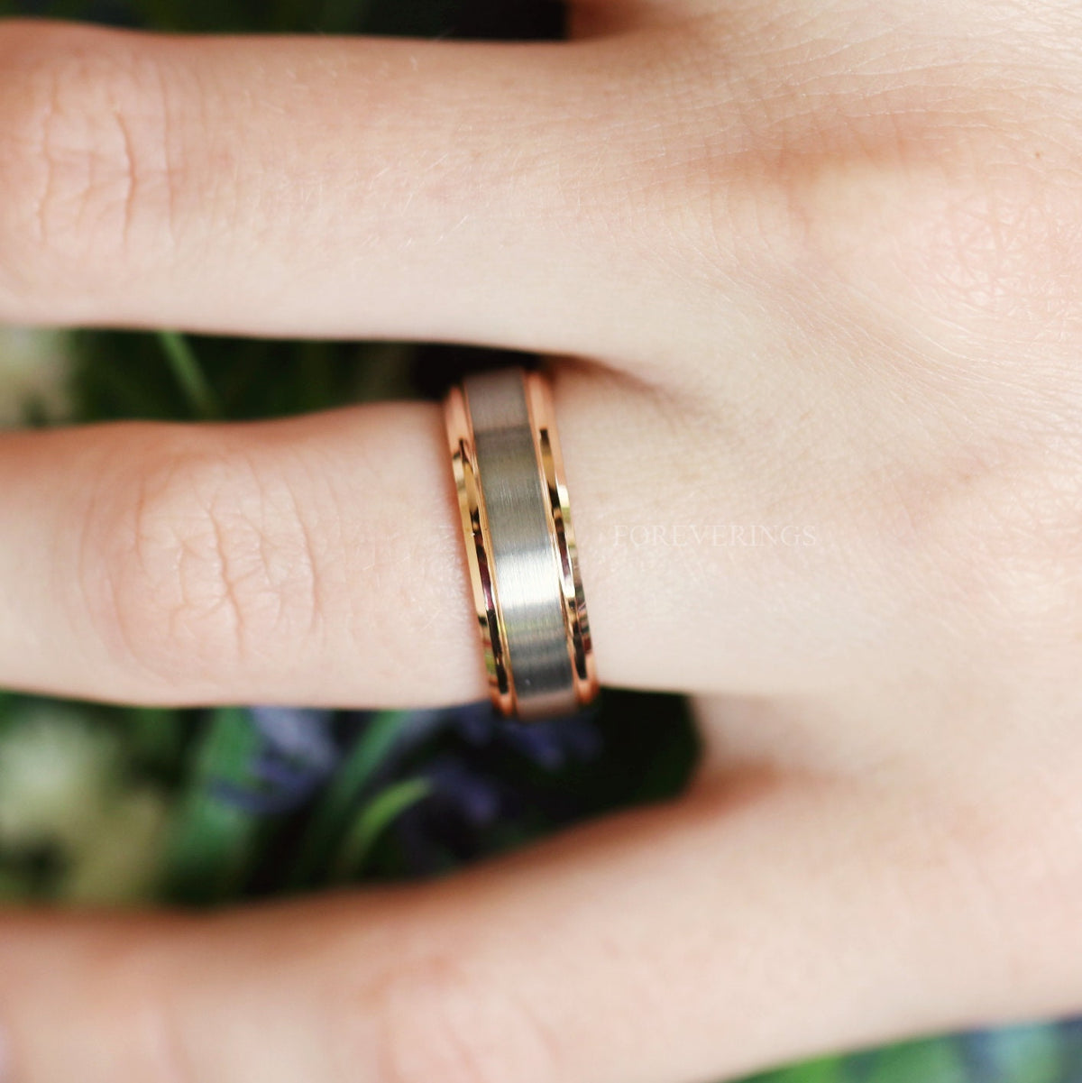 Men's two-tone silver and rose gold tungsten band worn on a hand, wider view