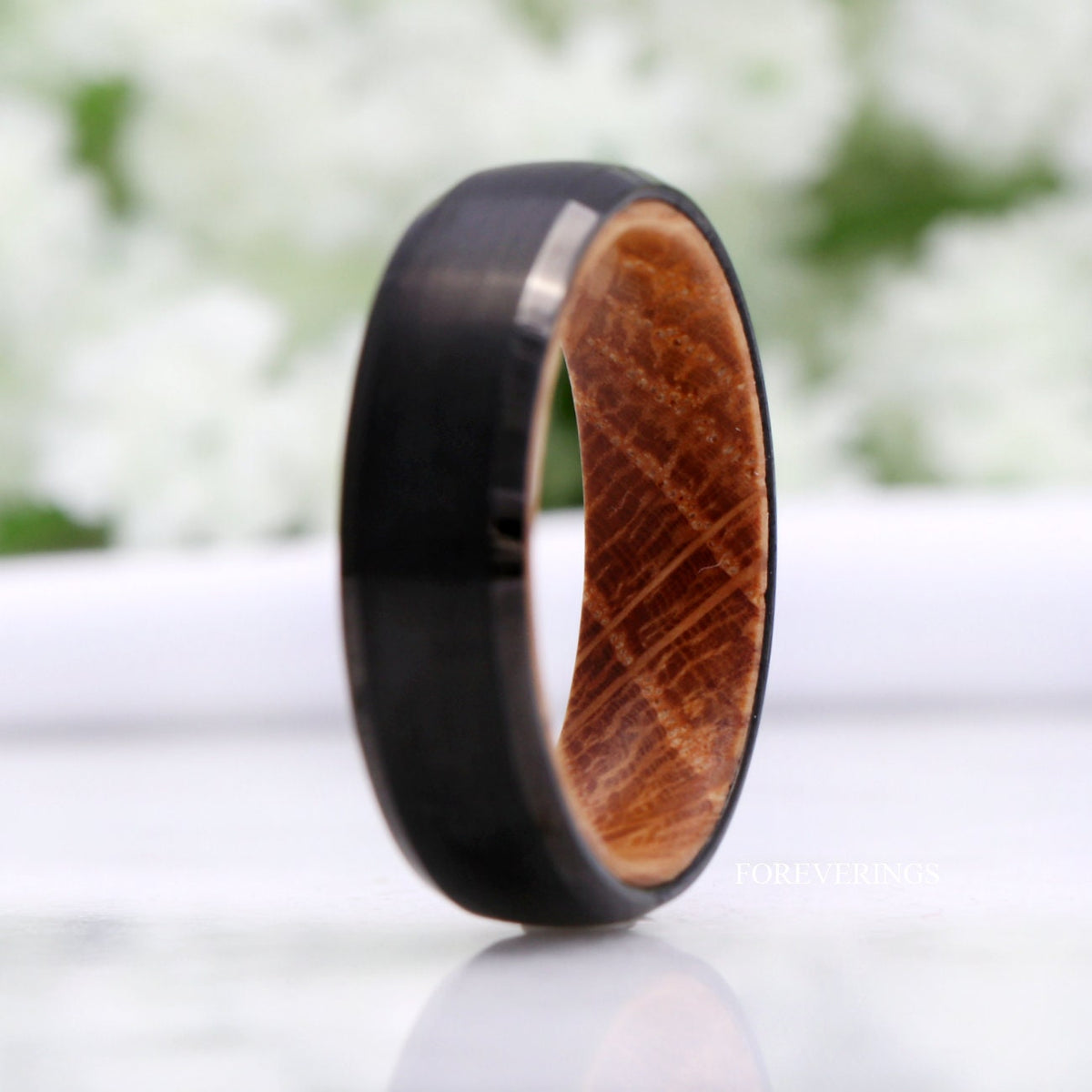 Black tungsten whiskey barrel wood band standing on edge, wider angled view
