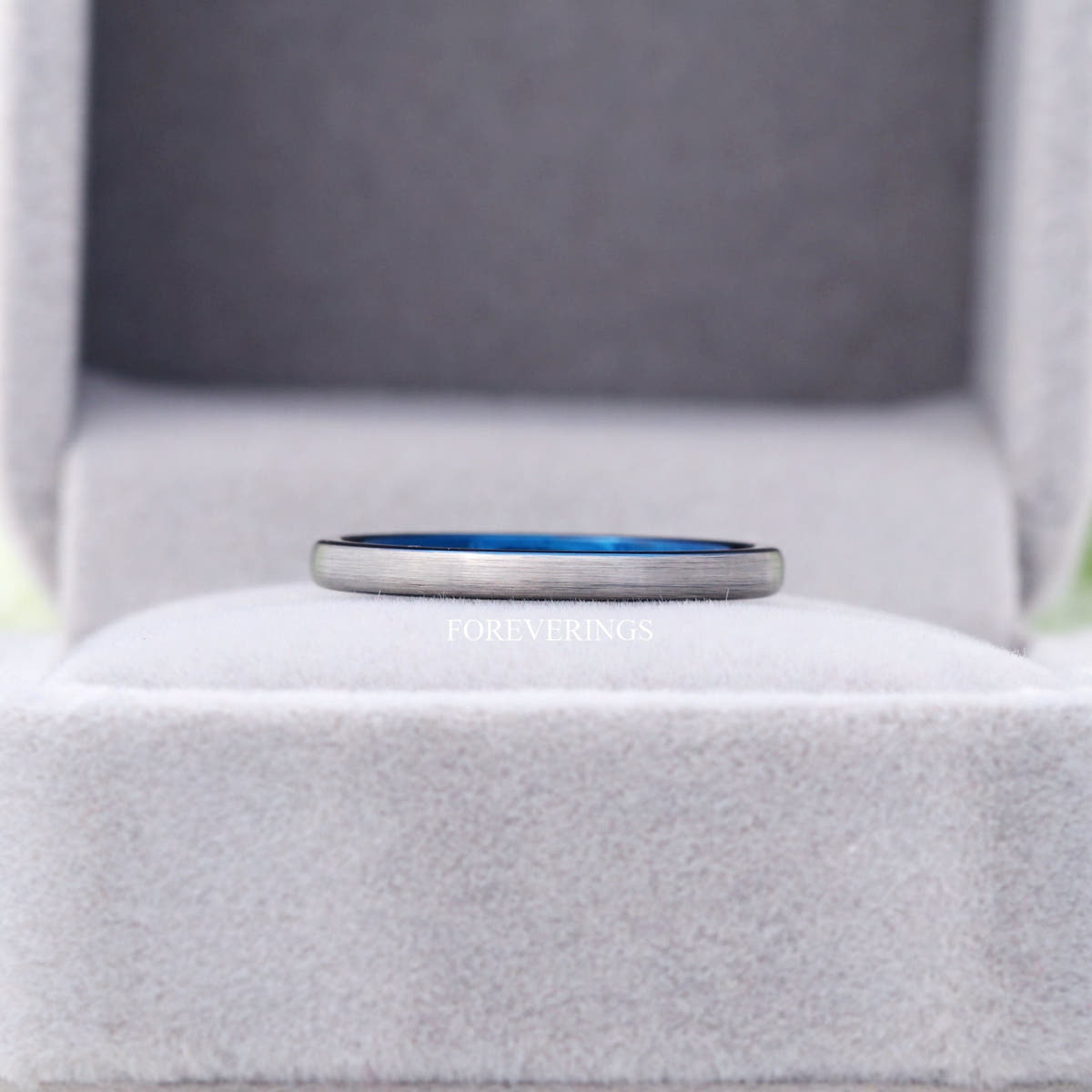 2mm silver and blue tungsten band lying in a gray velvet ring box