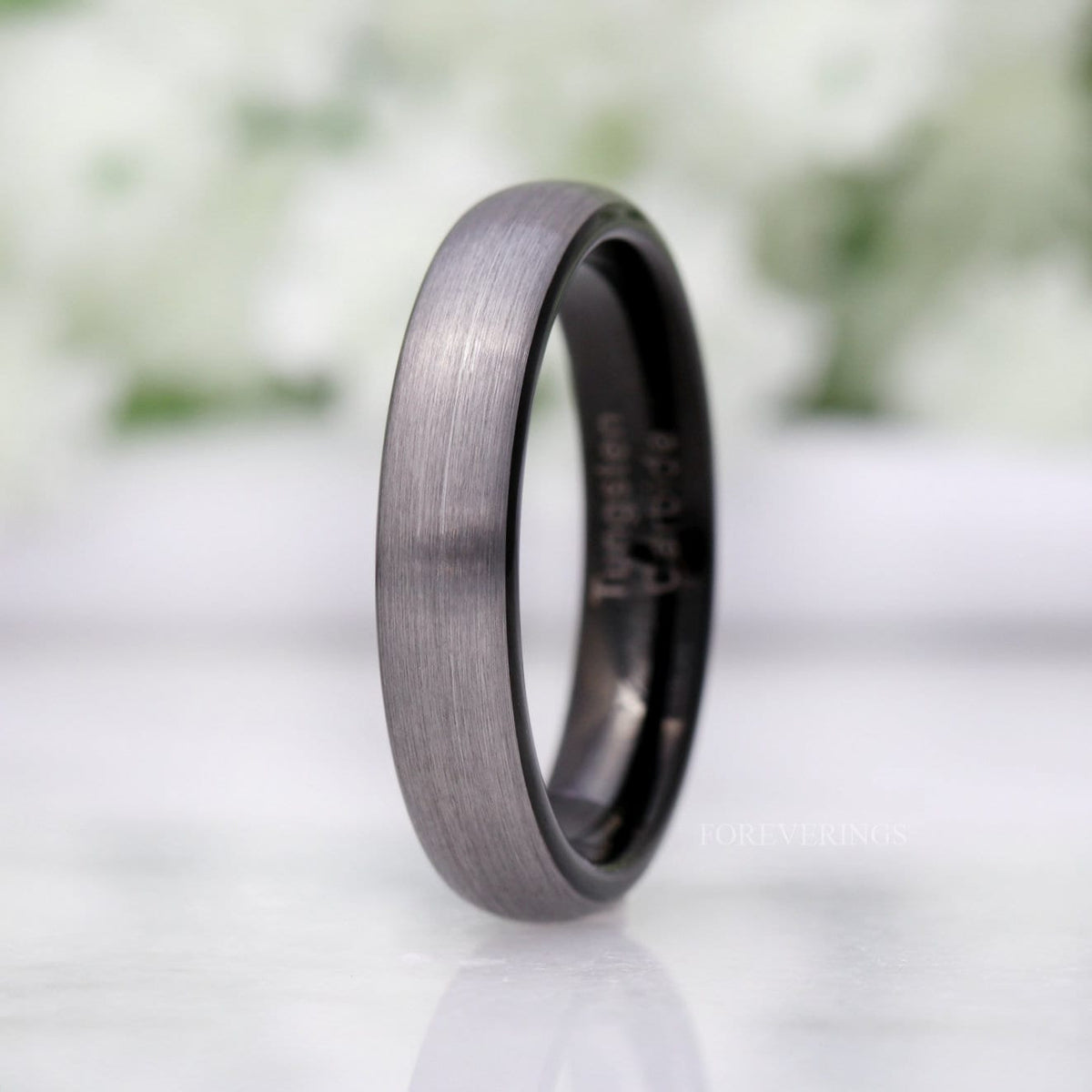 4mm matte silver tungsten band with a black interior, standing at an angle