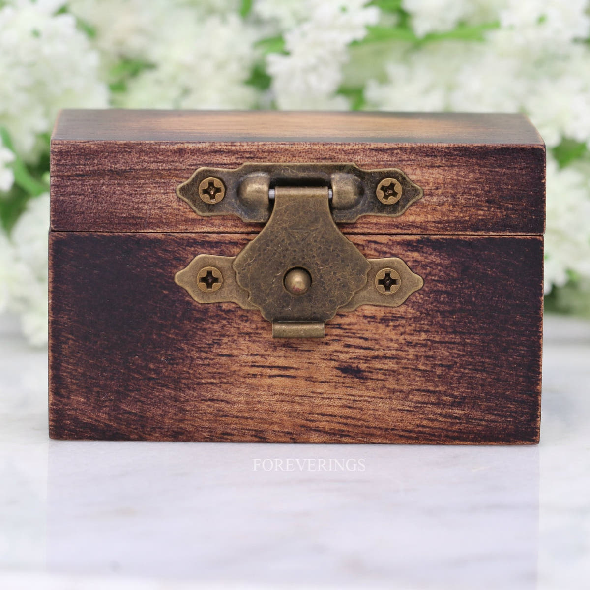 Closed wood ring box shown straight on with its brass front clasp