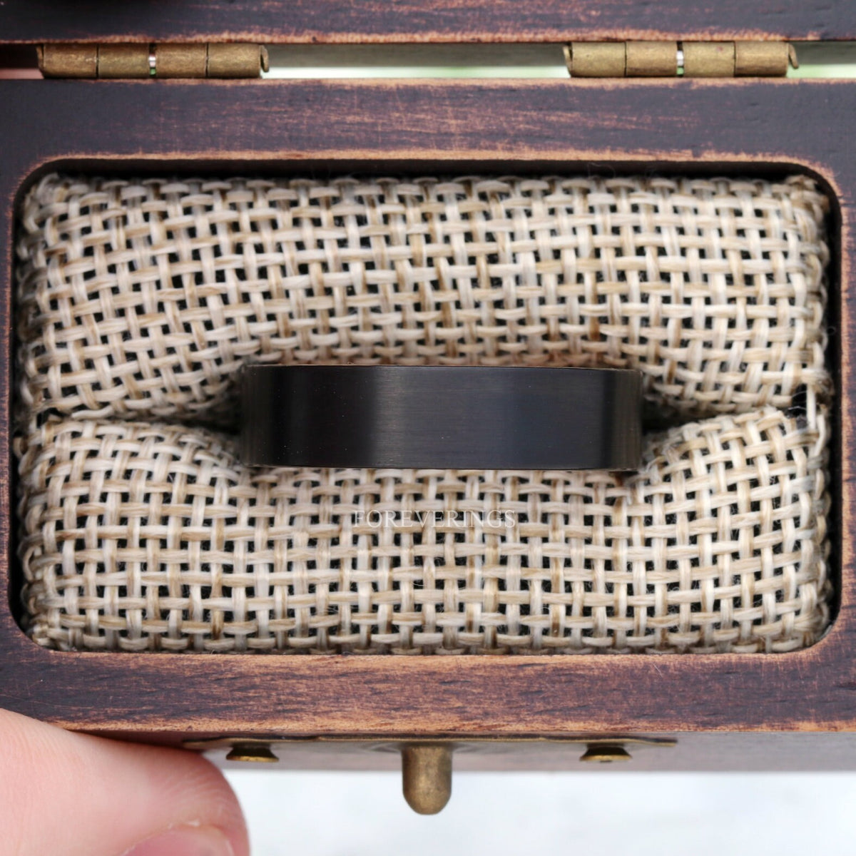 Black tungsten whiskey barrel wedding band in a rustic wood ring box with burlap insert