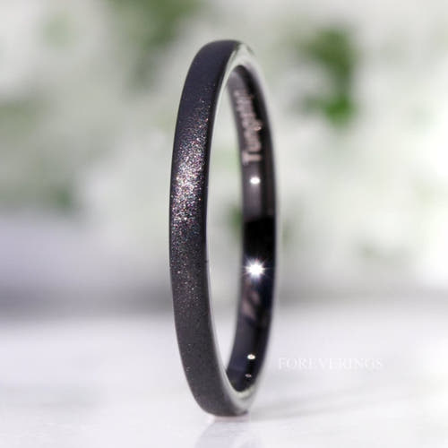 Minimalist 2mm black sandblasted tungsten ring standing on edge, close crop of the sparkling finish