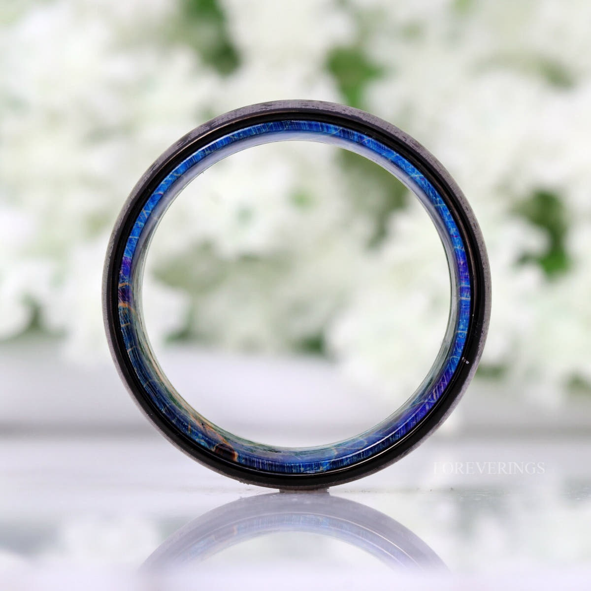 Black tungsten band viewed head-on through the center, showing the blue wood sleeve edge