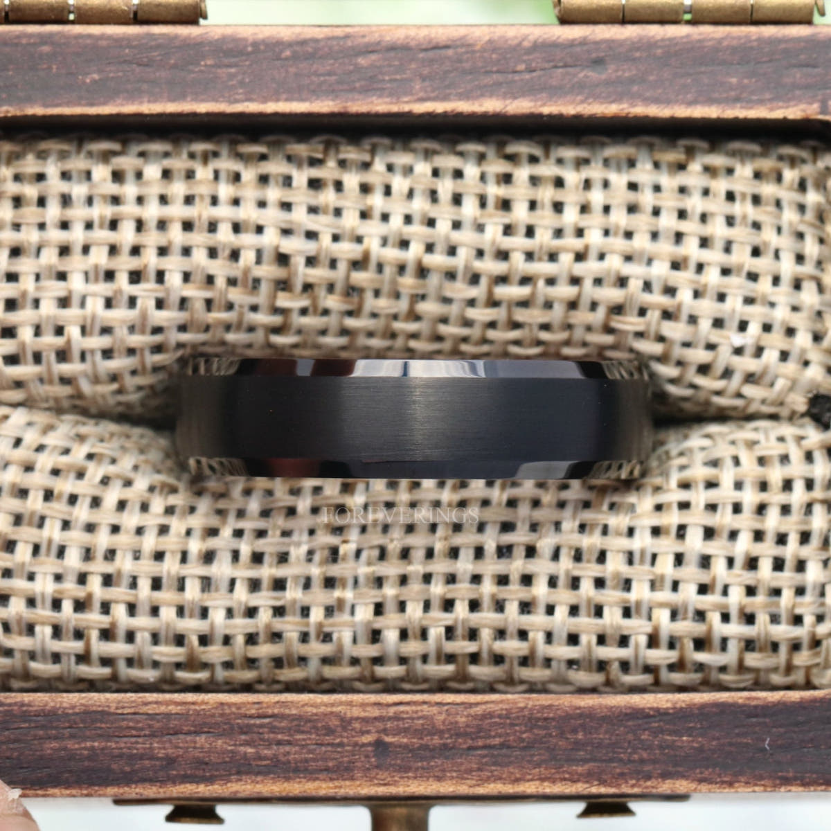 Black tungsten wedding band in a rustic wood ring box with burlap insert