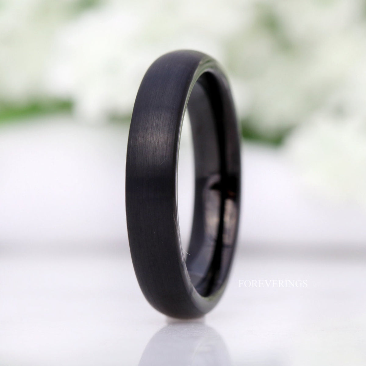 Minimalist 4mm brushed black tungsten band standing upright, domed edge straight on