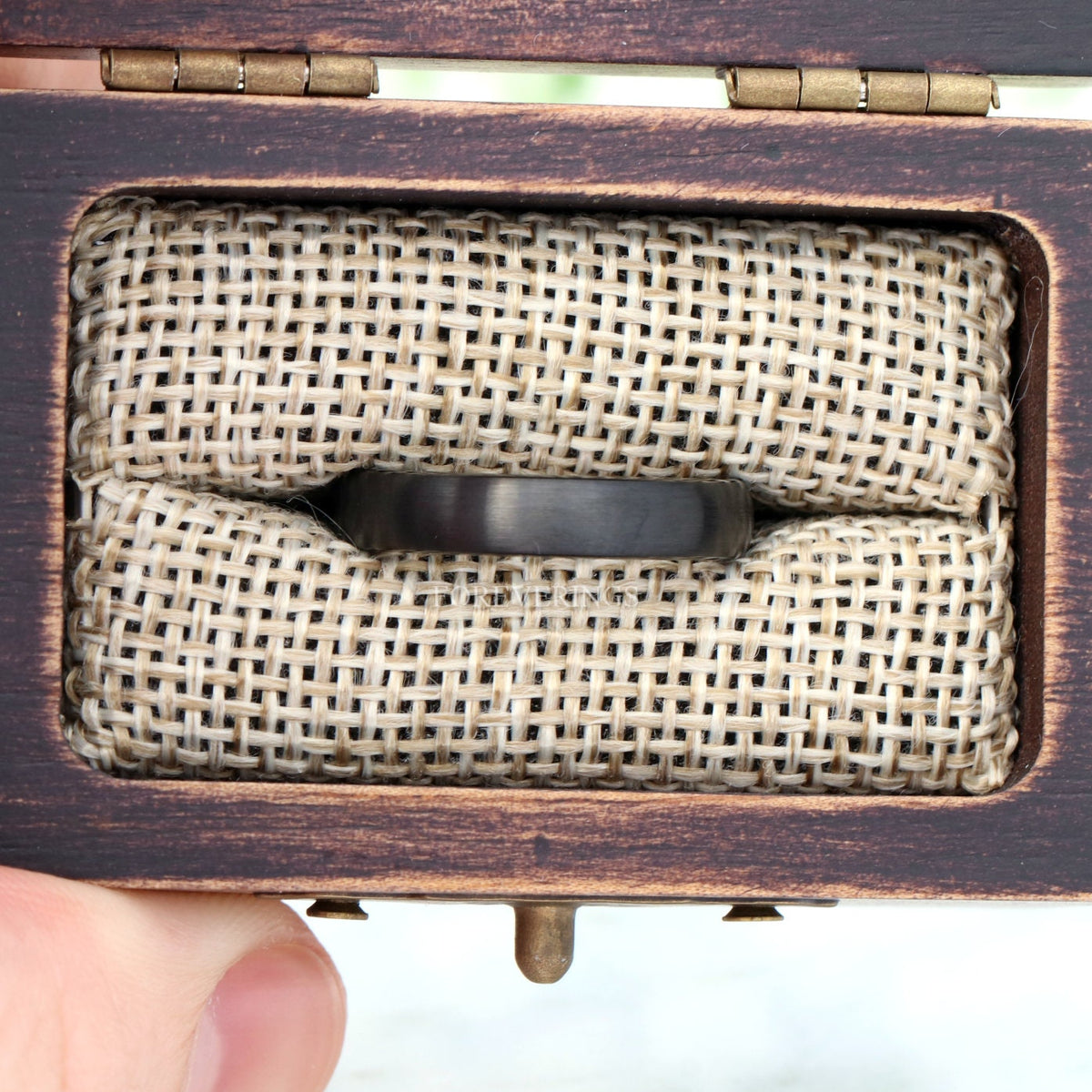 4mm matte black tungsten band in an open wood ring box, straight on
